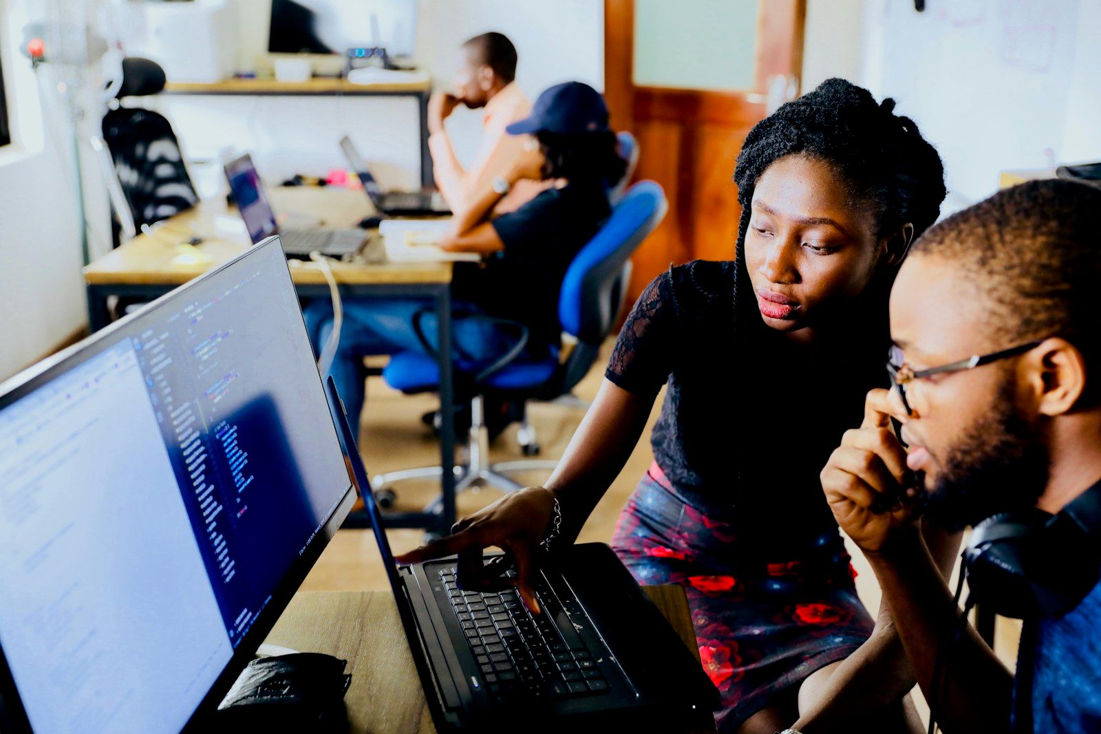Two engineers comparing output together on a desktop monitor