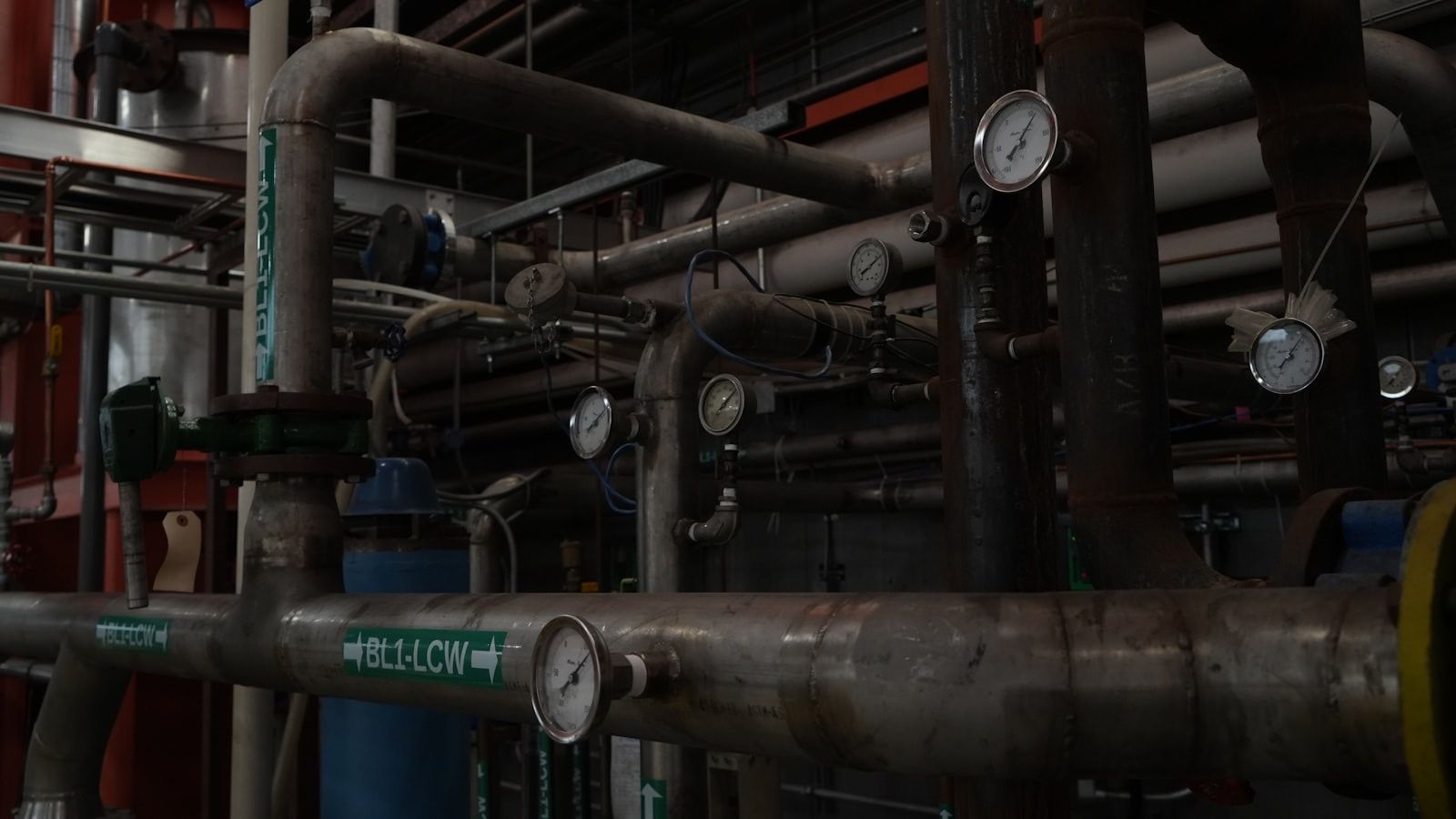 A dense run of industrial pipes with pressure gauges mounted along them.